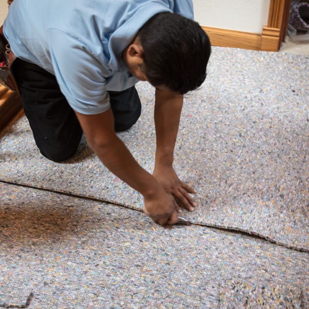 https://flooringinstallationconyersga.com/wp-content/uploads/2025/11/trimming-the-carpet-padding.jpg