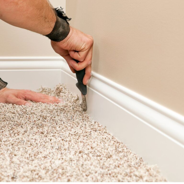 Professional carpet installer trimming and tucking carpet edges along baseboard during residential carpet installation in Conyers GA and Atlanta GA homes.