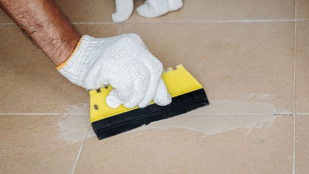 Professional tile installer applying grout between ceramic tiles during floor installation in Conyers GA and Atlanta GA homes.