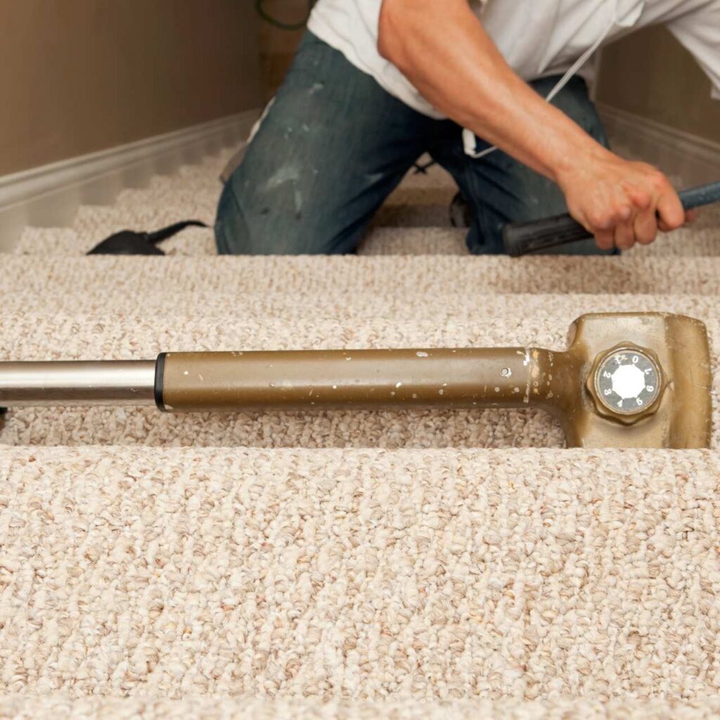 Carpet installer stretching and fitting new carpet on stairs during professional carpet installation in Conyers GA and Atlanta GA homes.