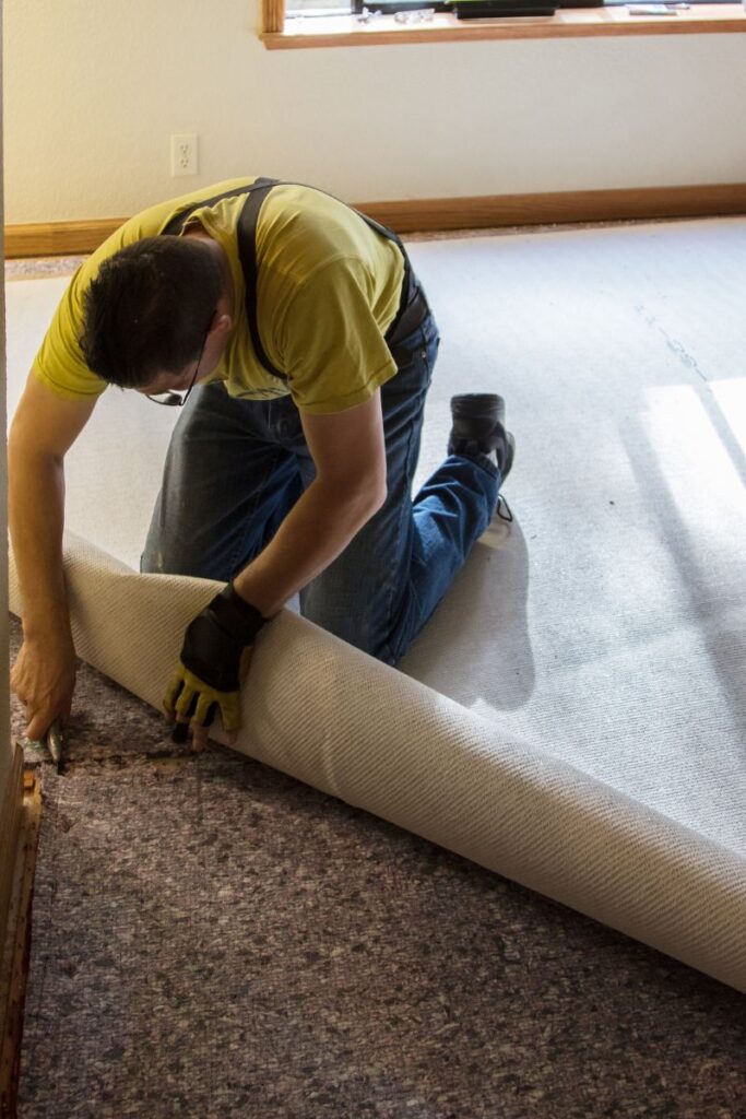 Professional carpet installer in Conyers GA removing old flooring and preparing the subfloor for new carpet installation in a residential home.
